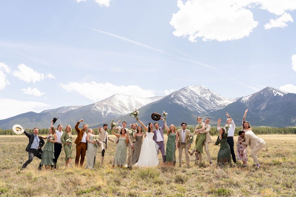 Wedding party mid-jump in a high mountain meadow at Buena Vista