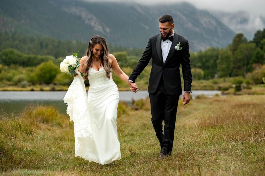 Couple walking hand in hand by a mountain lake on their wedding day