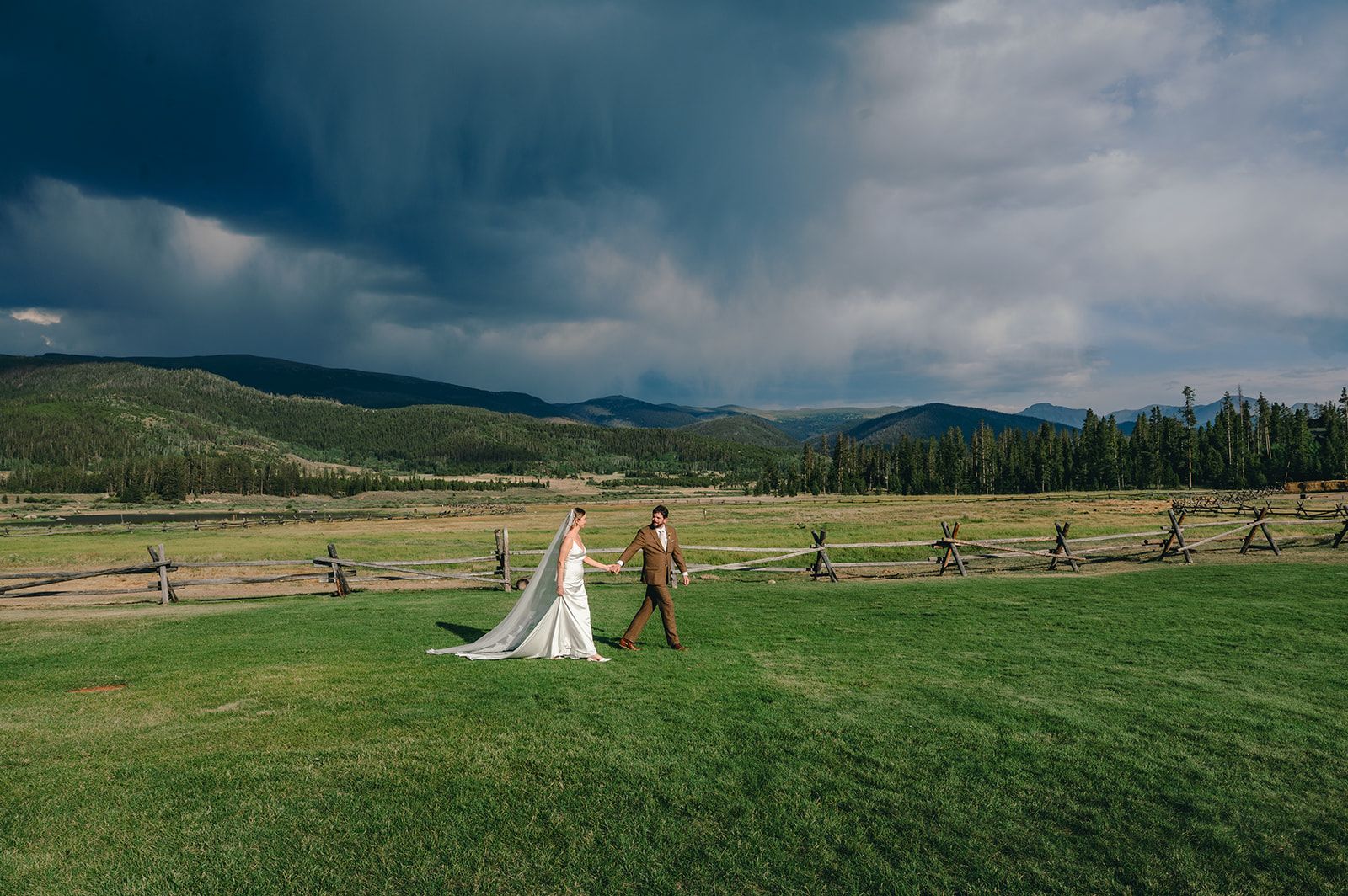 Couple walking a mountain ranch field under a dramatic sky
